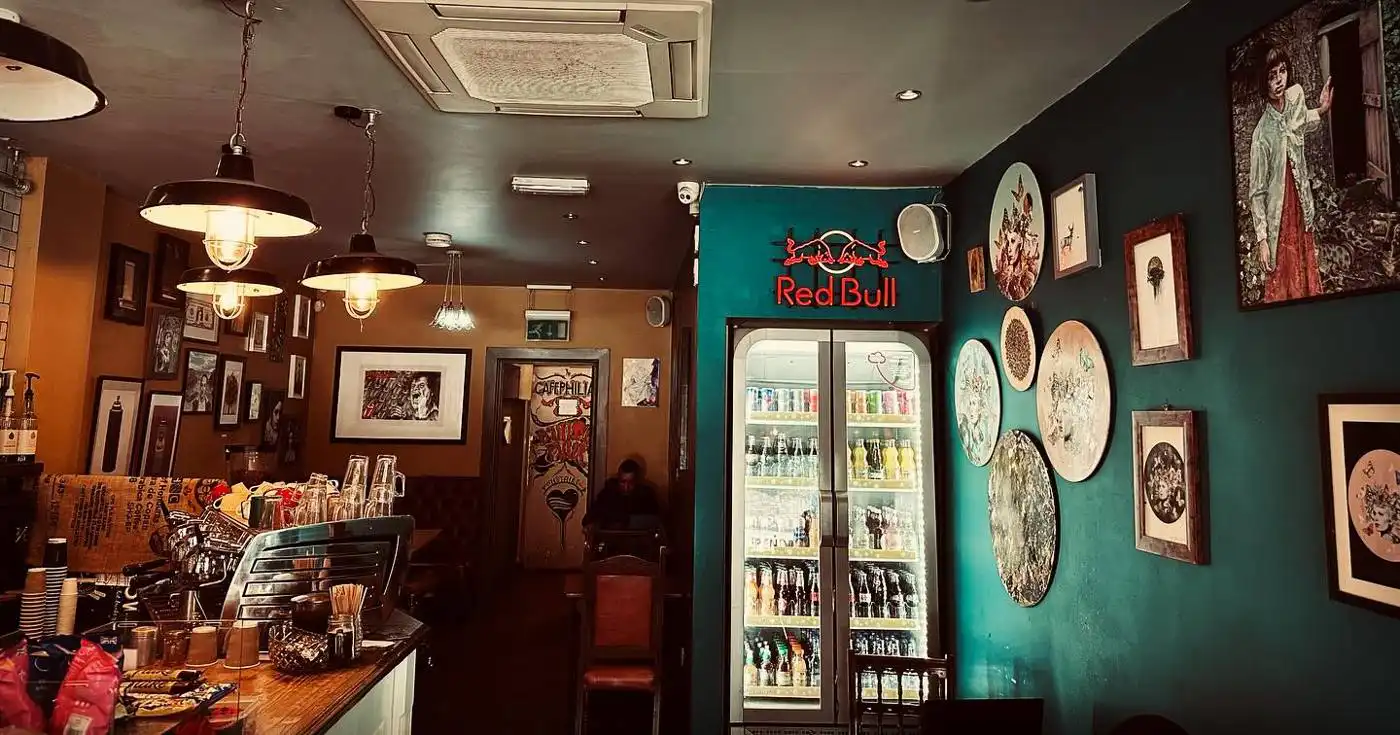 Teal wall with framed art and pendant lamps inside the café